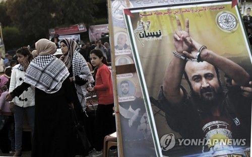 바르구티의 대형 포스터 옆에 서있는 팔레스타인인들