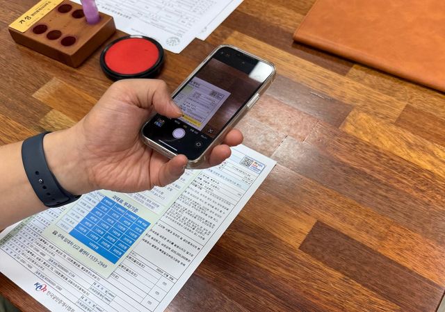 계약서 상의 '주택 임대차계약 즉시 신고 QR코드'를 스캔하는 모습