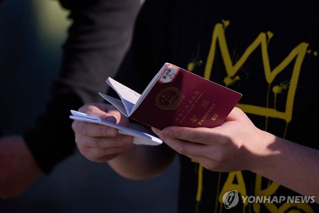 지난해 6월 한 중국인이 미국-멕시코 국경이 있는 캘리포니아주 제이쿰바에서 입국 심사를 받기 위해 여권을 들고 대기하고 있다. [EPA=연합뉴스]