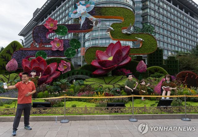 베이징 시내의 한 열병식 기념 화단 앞에서 사진찍는 시민