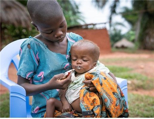세이브더칠드런 지원 보건센터 밖에서 동생에게 영양실조 치료식을 먹이는 아동