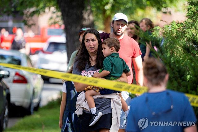 27일(현지시간) 미국 미네소타주 미니애폴리스 초등학교에서 발생한 총기사건 후 한 아이가 아이를 끌어안고 사건 현장을 바라보고 있다. 