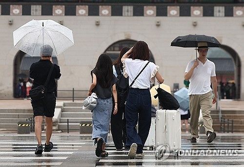 서울 종로구 광화문 인근에서 외국인 관광객이 비를 피하고 있다. [연합뉴스 자료사진]