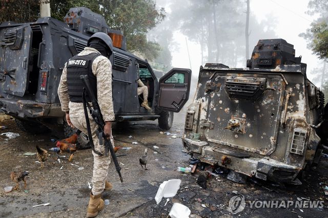 4일(현지시간) 불에 탄 경찰차량 인근 지나가는 아이티 경찰