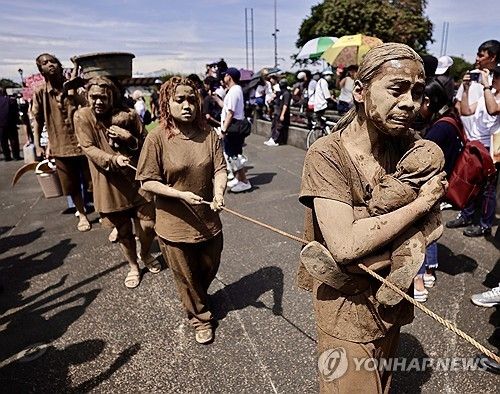 진흙을 뒤집어쓴 채 퍼포먼스를 하는 시위자들