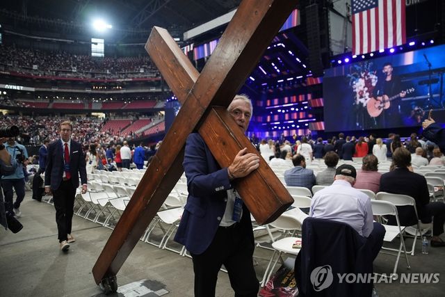 찰리 커크 추모식에 십자가 메고 온 참석자