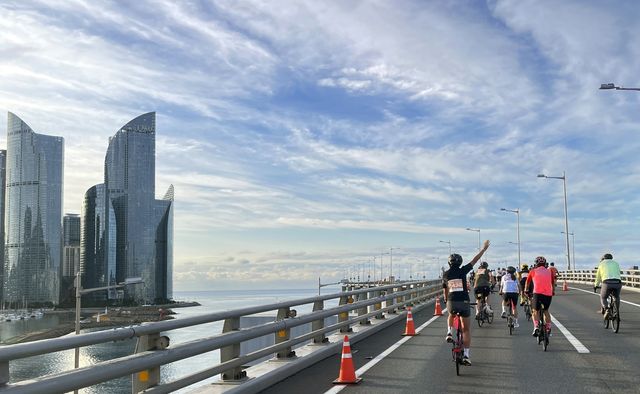 부산 마린시티와 바다가 보이는 광안대교 위로 지나가는 자전거 라이더.