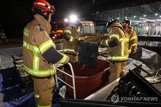 불에 탄 리튬이온 배터리 소화수조로 옮기는 소방대원