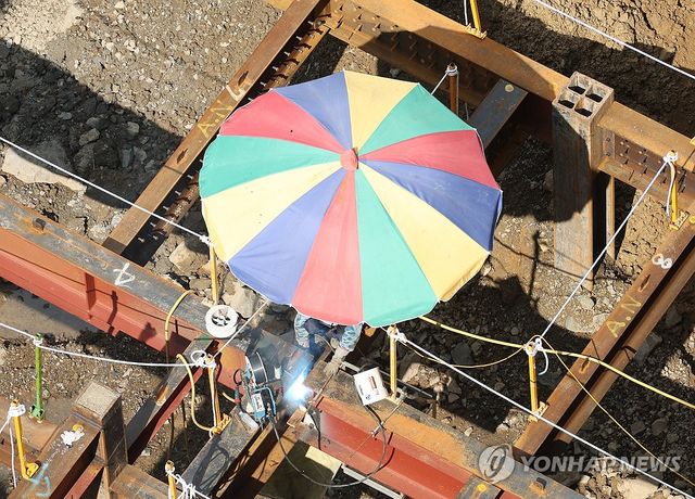 지난 8월 5일 대구 한 건설 현장 근로자가 햇볕을 막아주는 파라솔 아래에서 작업을 하고 있다. [연합뉴스 자료사진]