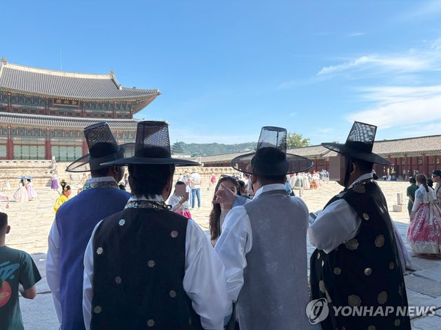 갓 쓰고 가이드 설명 듣고 있는 관광객들