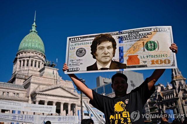 미국 100달러 지폐 디자인에 밀레이 대통령 얼굴을 합성해 만든 플래카드 든 아르헨티나 주민