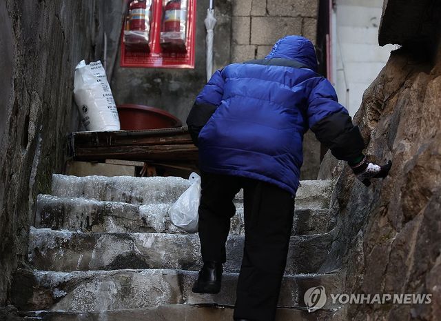 얼음이 언 계단을 힘겹게 오르는 한 어르신