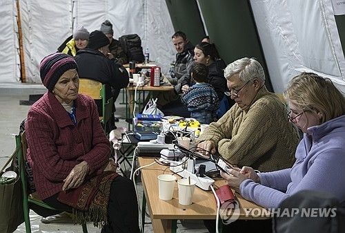 거리의 비상 대피 텐트에서 추위 피하며 스마트폰 충전하는 키이우 시민들