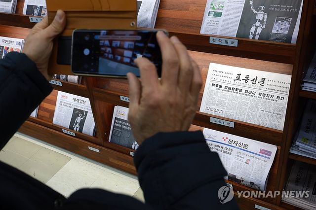 북한 노동신문 촬영하는 시민