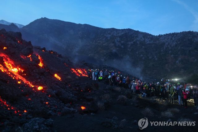 에트나 화산의 용암 흐름을 지켜보는 사람들