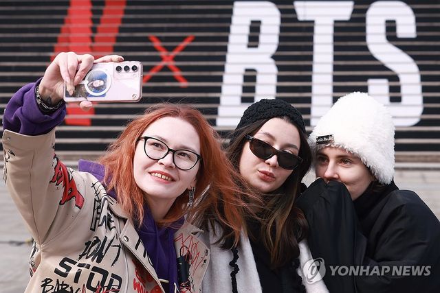 서울 종로구 세종문화회관 계단에서 방탄소년단(BTS) 공연 홍보물을 배경으로 기념촬영을 하는 관광객들