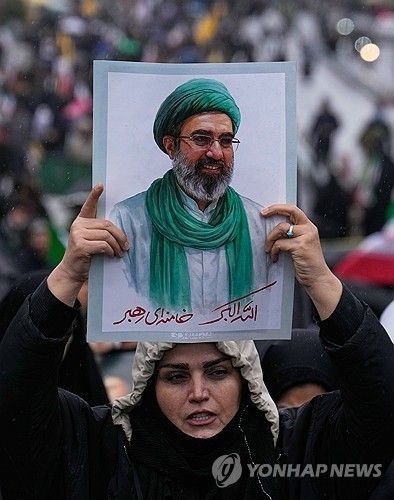 이란의 새 최고지도자 모즈타바 하메네이의 초상을 들고 있는 이란 여성.