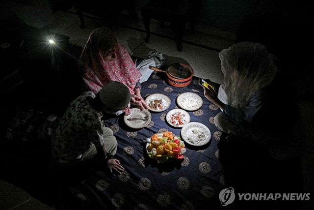 어둠 속에서 저녁을 먹는 파키스탄 가정