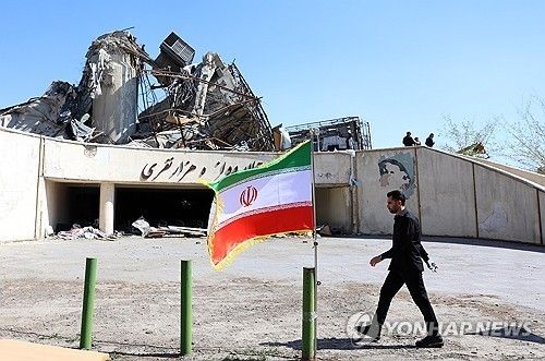 미국·이스라엘의 공습으로 부서진 건물 앞을 걷는 이란 관리