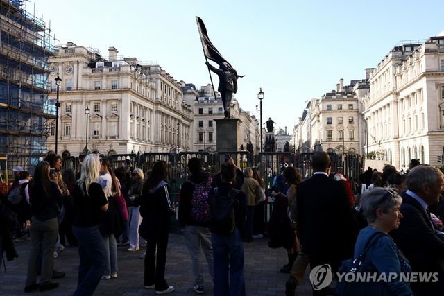 사람들이 뱅크시 동상을 보고 있다