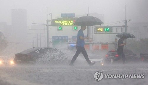 2023년 7월 13일 비가 쏟아지는 서울 여의대로 횡단보도 위로 우산을 쓴 시민들이 지나고 있다. [연합뉴스 자료사진]