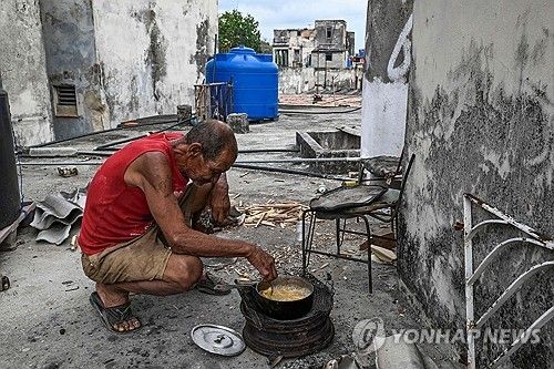 아바나에서 요리하는 남자. 가스가 없어 나무로 불을 때고 있다.
