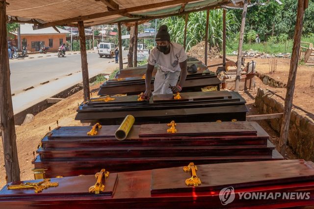 콩고민주공화국 부니아의 장의업체에서 한 남성이 관 위의 먼지를 닦고 있다.[AP=연합뉴스. 재판매 및 DB 금지]