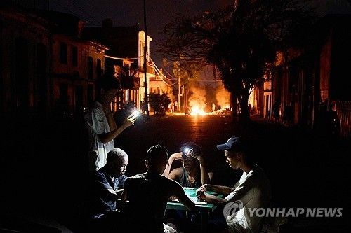 핸드폰 불빛에 의지해 도미노게임을 하는 쿠바인들