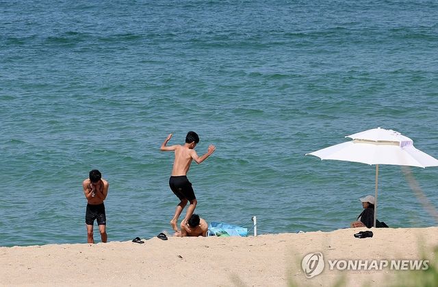 지난달 26일 강릉시 경포해변 백사장에서 한 가족이 시원한 바닷바람을 맞으며 더위를 식히고 있다. [연합뉴스 자료사진]