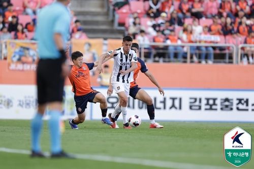 제주 선수 사이에서 공을 모는 서울 후이즈(가운데).
