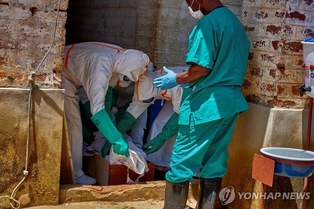 지난달 24일(현지시간) 콩고민주공화국 이투리주에서 보호장구를 착용한 적십자 요원들이 에볼라로 숨진 어린이의 시신을 수습하고 있다.[로이터=연합뉴스 자료사진. 재판매 및 DB 금지]