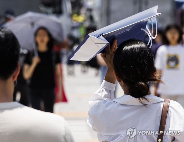 서울 종로구 광화문 건널목에서 한 시민이 쇼핑백으로 햇빛을 가리고 있다