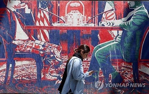 이란 테헤란의 옛 미국 대사관 인근에서 한 이란 소녀가 미국과 이란의 협상 테이블을 묘사한 반미(反美) 벽화 곁을 지나가고 있다. [EPA 연합뉴스. 재판매 및 DB 금지]