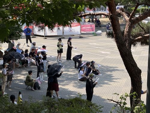 땡볕 더위에 그늘로 이동한 시위 참가자들