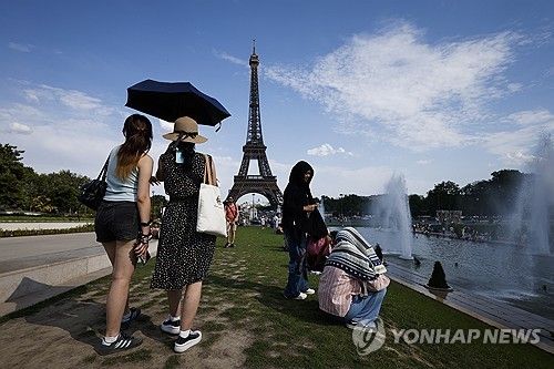 에펠탑 근처 우산으로 햇빛 가린 관광객들