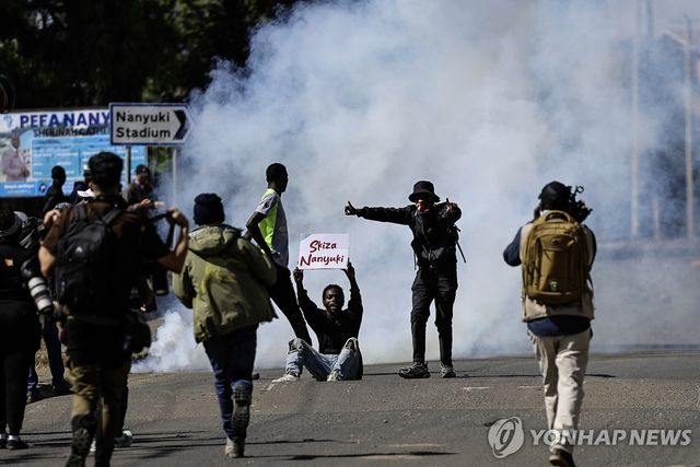 9일 케냐 나뉴키에서 미국인 대상 에볼라 격리·치료 시설 설치를 반대하는 시위 참가자가 최루탄이 터진 가운데 거리에 앉아 구호를 외치고 있다.[EPA=연합뉴스. 재판매 및 DB 금지]