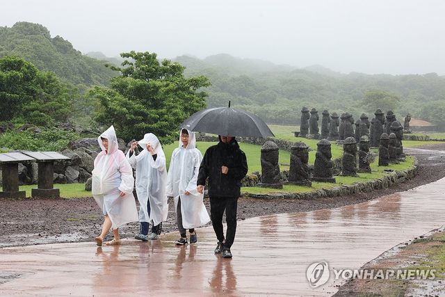 지난 24일 제주시 조천읍 교래리 제주돌문화공원을 찾은 관광객들이 우산과 우비 등을 갖추고 야외 전시물을 감상하고 있다. [연합뉴스 자료사진]