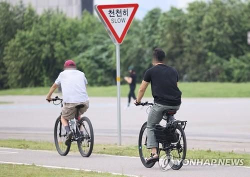 안전모를 착용하지 않은 채 자전거를 타는 사람들