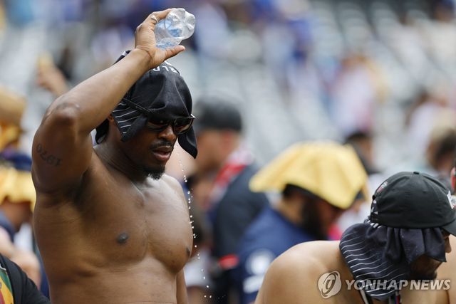 더위를 피해 머리에 물을 뿌리는 축구 팬