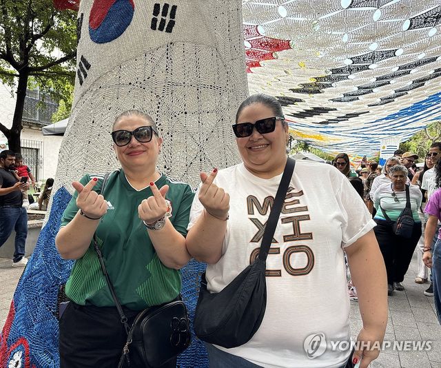 태극기 조형물 아래서 손 하트 포즈 짓는 아드리아나 케레로씨(좌측)