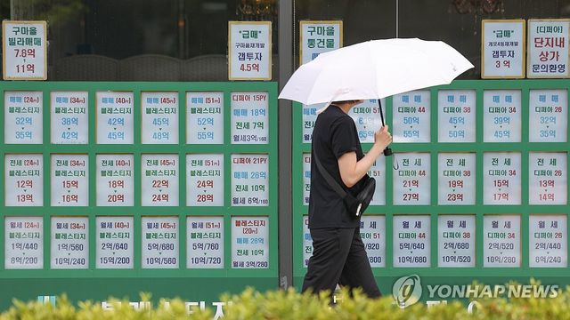 8일 양산 쓴 시민이 서울 강남구 한 부동산중개업소 앞을 지나고 있다. [연합뉴스 자료사진]