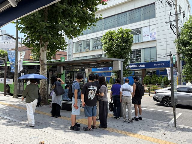 나무 그늘에 모여 버스 기다리는 시민들
