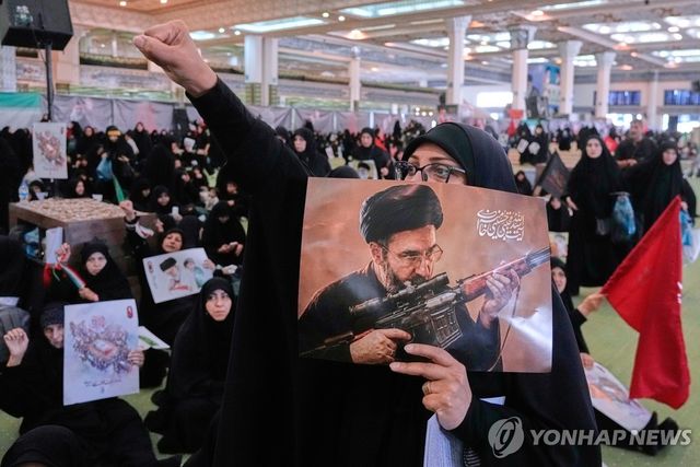 지난 14일(현지시간) 이란 테헤란의 이맘 호메이니 모살라 그랜드 모스크에서 한 여성이 아야톨라 세예드 모즈타바 하메네이 이란 최고지도자의 모습이 담긴 포스터를 들고 있다. [AP=연합뉴스 잘사진. 재판매 및 DB 금지]
