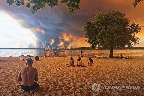 24일 프랑스 남서부 해안가 피서객들 눈앞에 거대한 산불 연기가 피어오르고 있다.