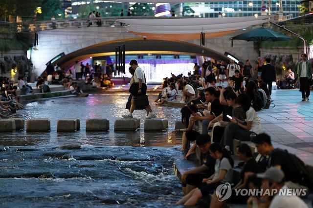 열대야주의보가 내려진 서울 청계천에서 발을 담그고 휴식을 취하는 시민·관광객들