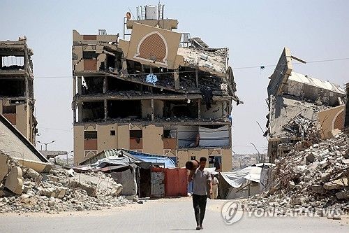 가자지구 칸유니스에서 한 피란민이 이스라엘군에 의해 파괴된 건물 잔해 앞을 걸어가고 있다. [AFP 연합뉴스. 재판매 및 DB 금지]