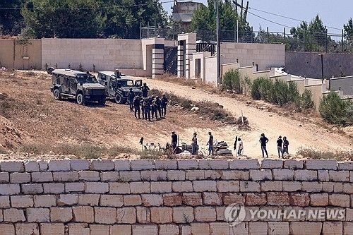 요르단강 서안 나블루스 남부 쿠스라 마을의 팔레스타인 주민 가옥 앞에서 이스라엘 군인들이 정착민들(앞쪽) 옆에 선 채 경계를 서고 있다.[AFP 연합뉴스. 재판매 및 DB 금지]