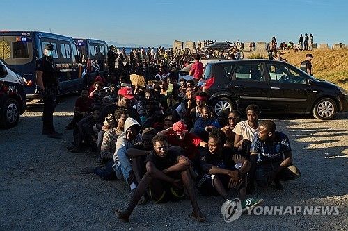 지난 3일 세우타에서 음식 배급을 받기 위해 줄지어 앉아 있는 이주민들 [AP=연합뉴스. 재판매 및 DB 금지] 