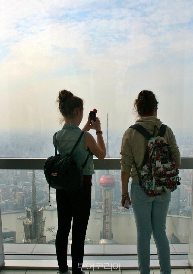 상하이 세계금융센터(Shanghai World Financial Center)에서 동방명주탑 등 풍경을 내려다보며 사진을 찍는 여행객/사진-투어코리아