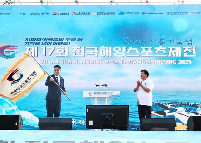 제18회 전국해양스포츠제전 개최지로 선정된 경남 거제시의 민기식 부시장(왼쪽)이 임병택 시장으로부터 대회기를 전달받아 흔들고 있다./사진=시흥시